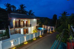 a house with a lit up facade at night at Blue Orchid Villa in Talpe