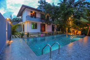 a swimming pool in front of a house at Blue Orchid Villa in Talpe