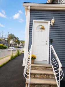 a white door on a blue house with stairs at Stay by Gina in Irvington