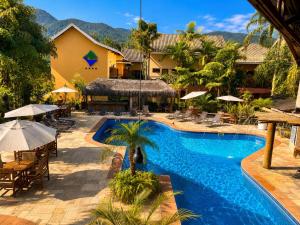 a pool at a resort with tables and umbrellas at Ilha Flat Apto 3207 in Ilhabela