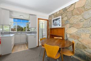 a kitchen and dining room with a stone wall at Rock On in Jindabyne