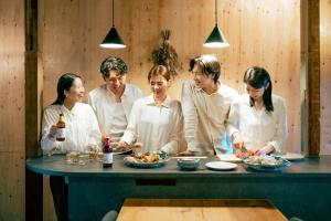 a group of people standing around a table eating food at まちの別邸 緝 shu in Kochi