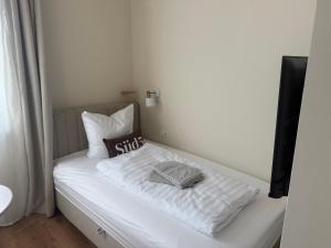 un letto con lenzuola e cuscini bianchi in una stanza di Süd5 a Borkum
