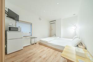 a white room with a bed and a microwave at コインズホステル天神ペット宿泊可 in Fukuoka