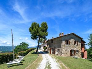 an old stone house with a tree on a dirt road at Flat on a farm with swimming pool and many activities in SantʼAngelo in Vado