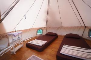 a tent with two beds in a room at Kabut Pinus Comfort Camp in Palasari