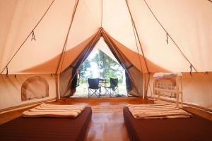 two beds in a tent with a table and chairs at Kabut Pinus Comfort Camp in Palasari