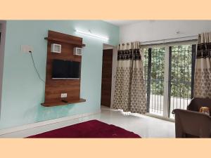 a living room with a tv and a window at The Grand Crest Residency in Panchgani