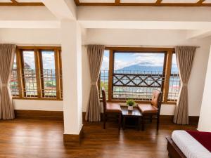 a living room with windows and a table and chairs at Gangtok Central Rooms in Gangtok