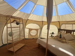 a tent with a bed and a ladder in a room at Sunset Tent in Sageau