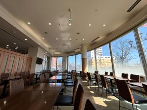 a dining room with tables and chairs and large windows at Lasting Hotel in Kushiro