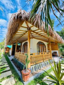 a house with a thatched roof and a palm tree at The Lauk private in Gili Islands
