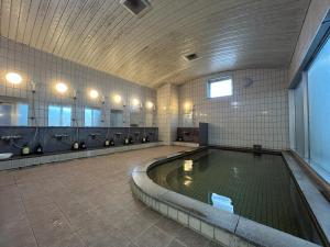 a swimming pool in a bathroom with sinks and mirrors at Lasting Hotel in Kushiro
