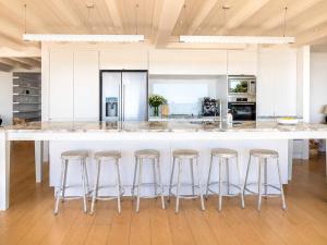 a kitchen with a large island with bar stools at No 63 - Stay Waiheke in Onetangi +30 photos