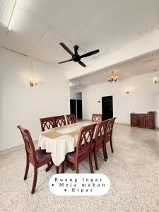 a dining room with a table and chairs and a ceiling fan at Harumi Guesthouse in Marang