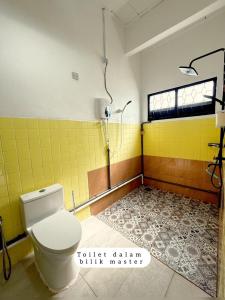 a bathroom with a toilet and a yellow wall at Harumi Guesthouse in Marang +7 photos