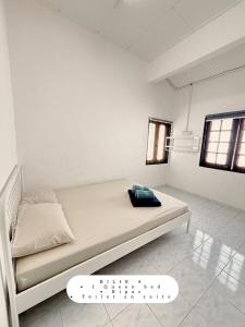 a bed in a white room with a scale at Harumi Guesthouse in Marang