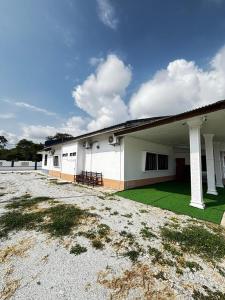 a large white building with a green lawn in front of it at Harumi Guesthouse in Marang