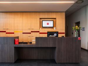an office with a reception desk with a tv on the wall at ibis Heverlee Leuven in Leuven