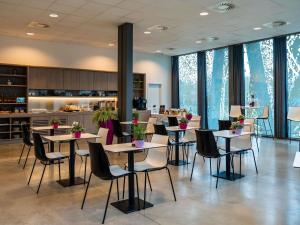 a restaurant with tables and chairs in a cafeteria at ibis Heverlee Leuven in Leuven
