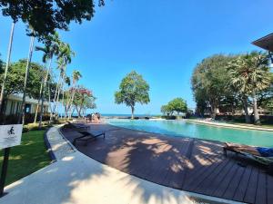 a swimming pool with people sitting on benches next to it at บ้านแสนสุขคอนโดติดทะเล By Nichahome in Hua Hin