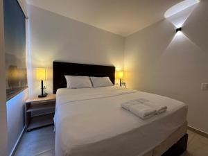 a bedroom with a large white bed with two lamps at Mejor Hotel, Centro Medellín, Opera, adults only entertainment in Medellín