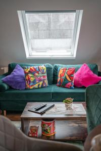 a living room with a green couch with colorful pillows at Familien Apartment bei Legoland 8 Min, Spielplatz & Netflix in Ichenhausen