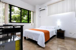 a white bedroom with a bed and a window at Hotel de Alborada - Cerca Del Aeropuerto in Guayaquil