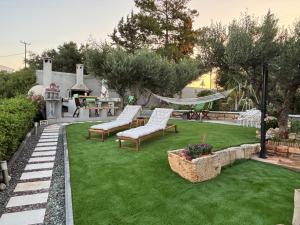 a backyard with green grass and two chairs and a hammock at Cretan stars villas Hersonissos in Hersonissos