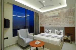a bedroom with a bed and a chair and a table at Hotel Shivora in Bathinda