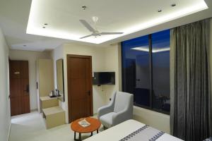 a hotel room with a bed and a chair and a window at Hotel Shivora in Bathinda