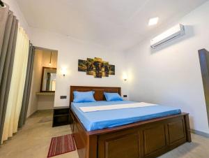a bedroom with a bed with blue pillows at TK Stay in Arugam Bay