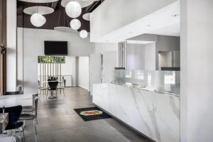 a kitchen with white cabinets and a dining room at Super 8 by Wyndham Riviera Beach West Palm Beach in Riviera Beach