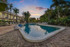 a swimming pool in a resort with palm trees at Super 8 by Wyndham Riviera Beach West Palm Beach in Riviera Beach
