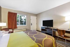 a hotel room with a bed and a flat screen tv at Super 8 by Wyndham Riviera Beach West Palm Beach in Riviera Beach