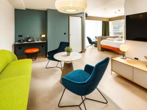 a living room with blue and green chairs and a bedroom at ibis Styles Edinburgh St Andrew Square in Edinburgh