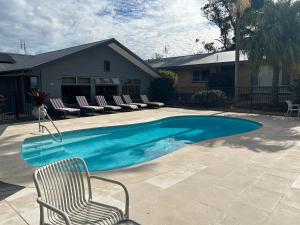 a swimming pool with a chair and chairs next to a house at Hunter Oasis in Morpeth