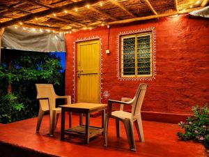 a patio with two chairs and a table and a house at Gowri Guest House in Hampi