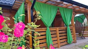 a gazebo with green curtains and pink roses at Domek Bursztyn in Święta Katarzyna