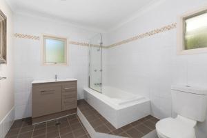 a white bathroom with a tub and a toilet and a sink at Rock On in Jindabyne +14 photos