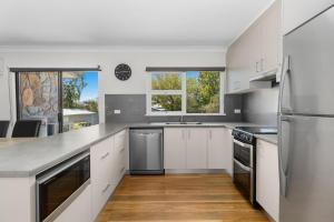 a kitchen with white cabinets and stainless steel appliances at Rock On Cottage in Jindabyne