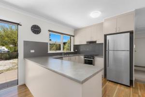 a kitchen with white cabinets and a stainless steel refrigerator at Rock On Cottage in Jindabyne