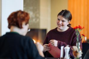 a woman laughing while sitting at a table at Stasjonen Hotel Lillehammer in Lillehammer