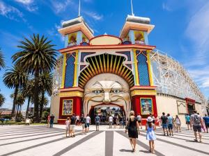 a crowd of people walking in front of a building with a giant face at Canvas On Barkly Apartments St Kilda in Melbourne