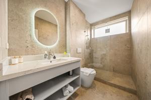 a bathroom with a sink and a toilet and a mirror at Canvas On Barkly Apartments St Kilda in Melbourne +34 photos
