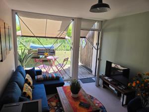 a living room with a blue couch and a tv and a patio at Le Cercle de Victoria stationnement privé petit déjeuner compris in Bourges