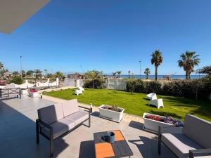 a patio with couches and a lawn with palm trees at VillaVenere in Rossano