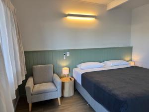 a bedroom with a bed and a chair and a lamp at Pearly Shell Motel in Bowen +12 photos