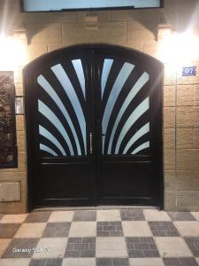 a black door in a room with a checkered floor at Joli F3 in Dar el Beïda