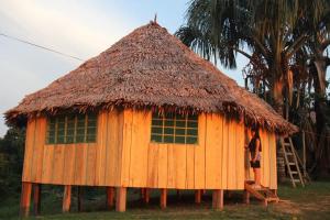 a man standing in a hut with a thatch roof at Hostal Maguare-Reserva Indígena Maguare in Leticia